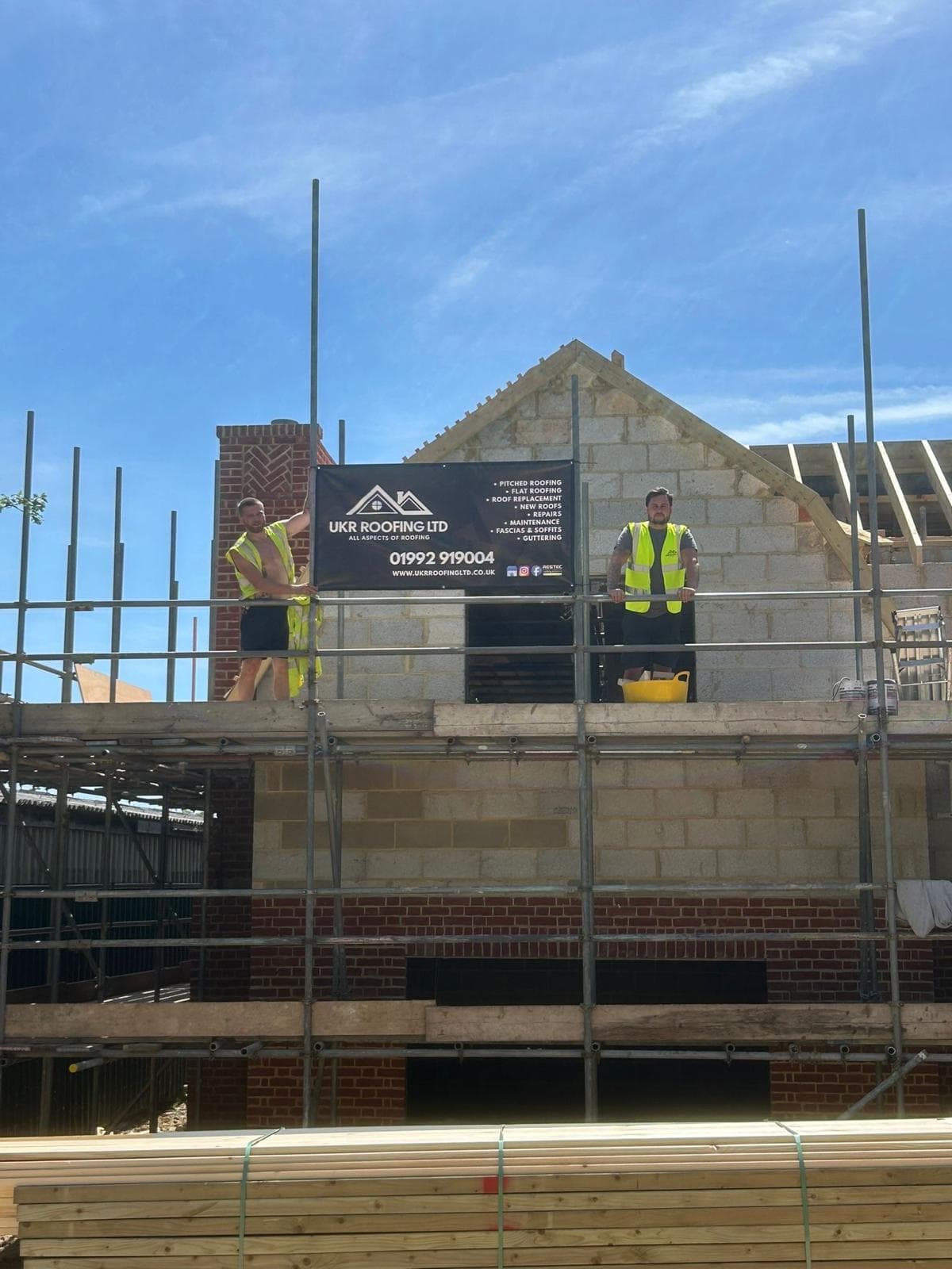 UKR Roofing team with company banner on scaffolding
